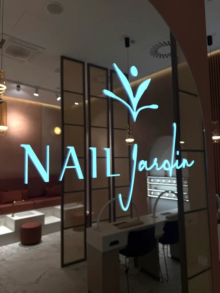 Svítící logo Nail Jardin v zrcadle s výhledem na interiér salonu